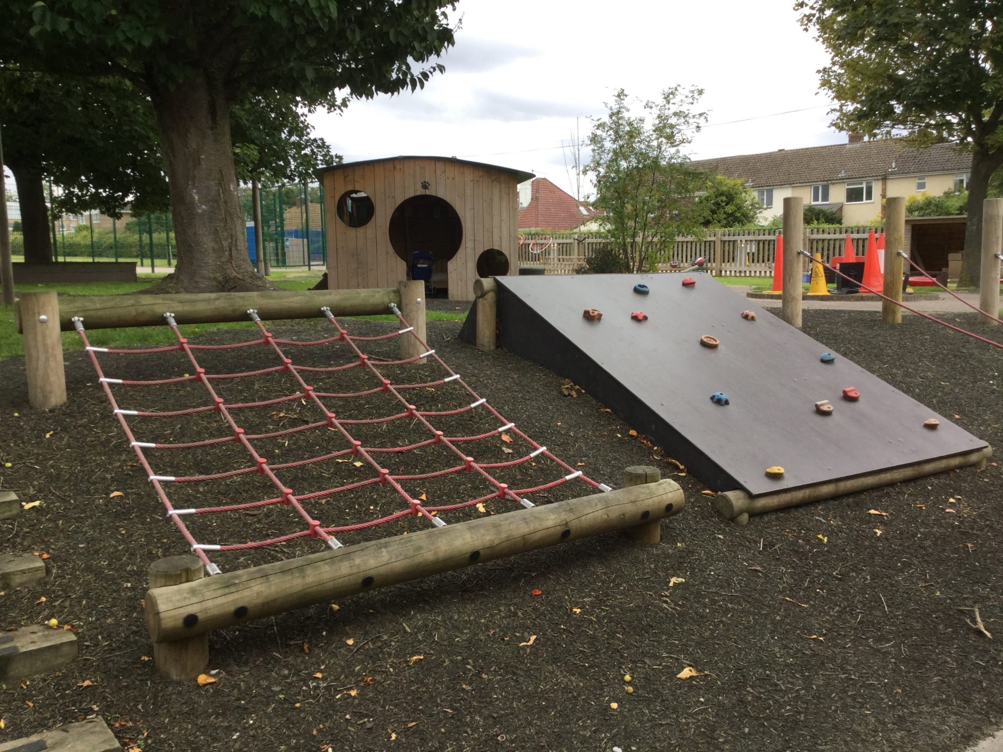 The early Years outdoor space showing the climbing net and climbing slope with a playhouse in the background.