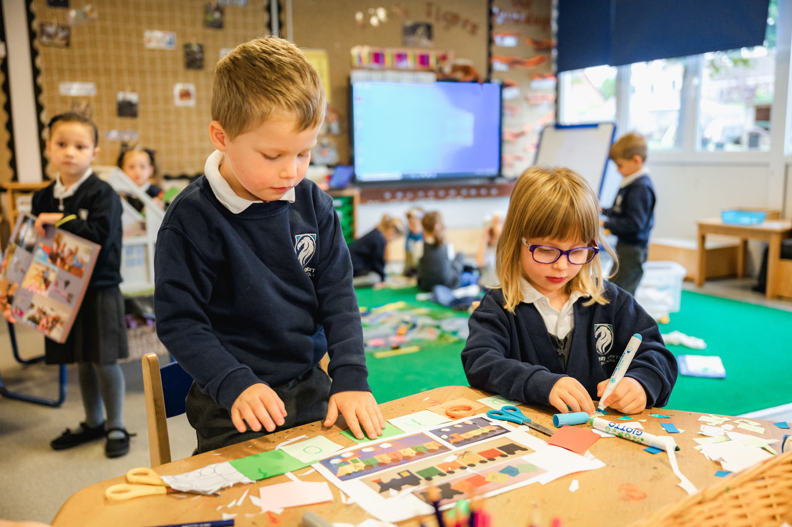 A boy and girl are engaged in activity at the mark making table