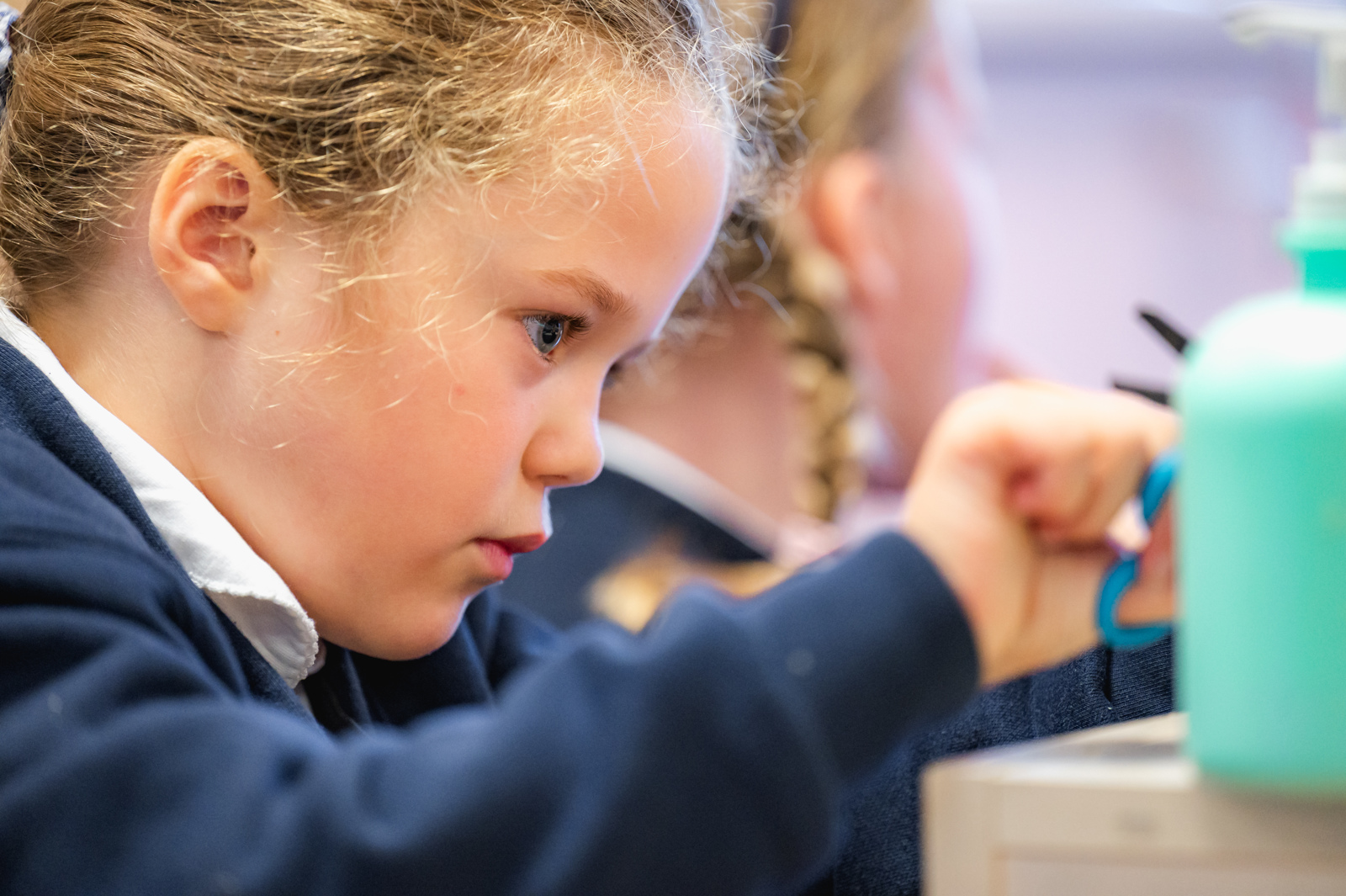 Close up image of a girl, deep in concentration as she uses scissors